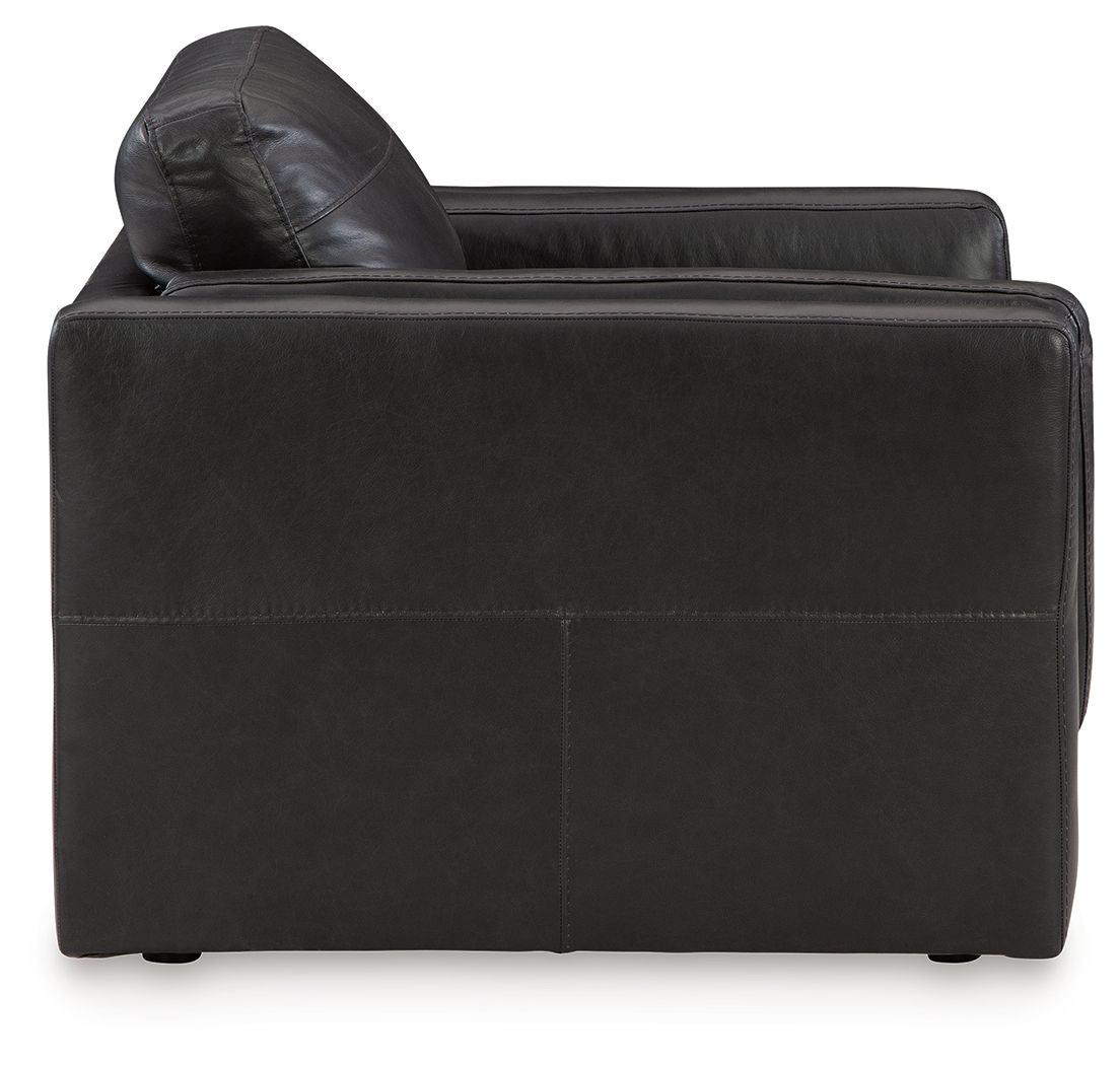 Amiata onyx chair and a half with dark leather, rounded headrest and bolster arms.