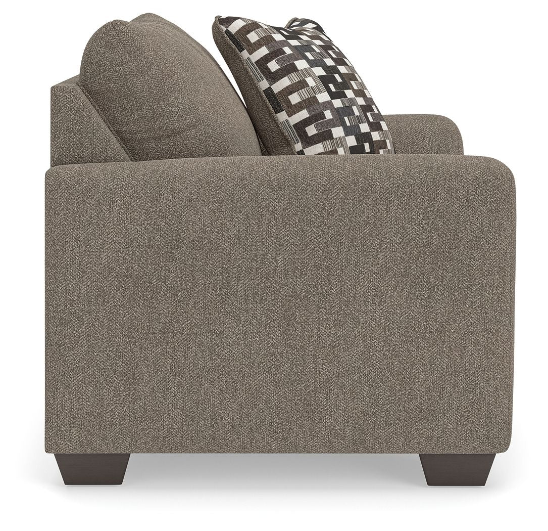 Upholstered chair and a half with dark gray fabric and geometric patterned back pillow