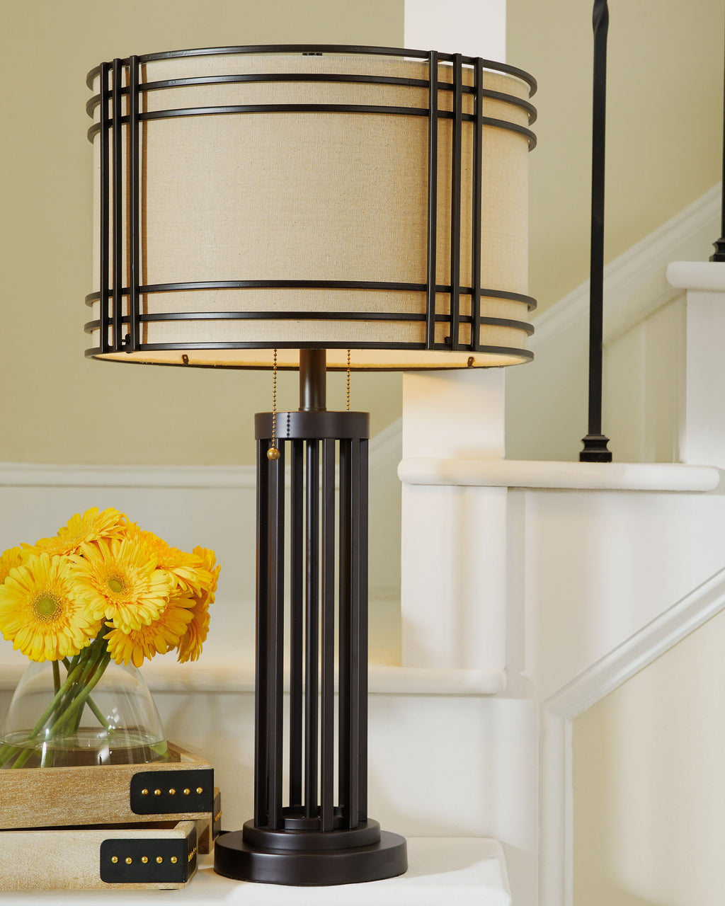 Dark brown metal table lamp with beige drum shade and cylindrical base
