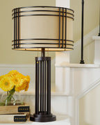 Dark brown metal table lamp with beige drum shade and cylindrical base