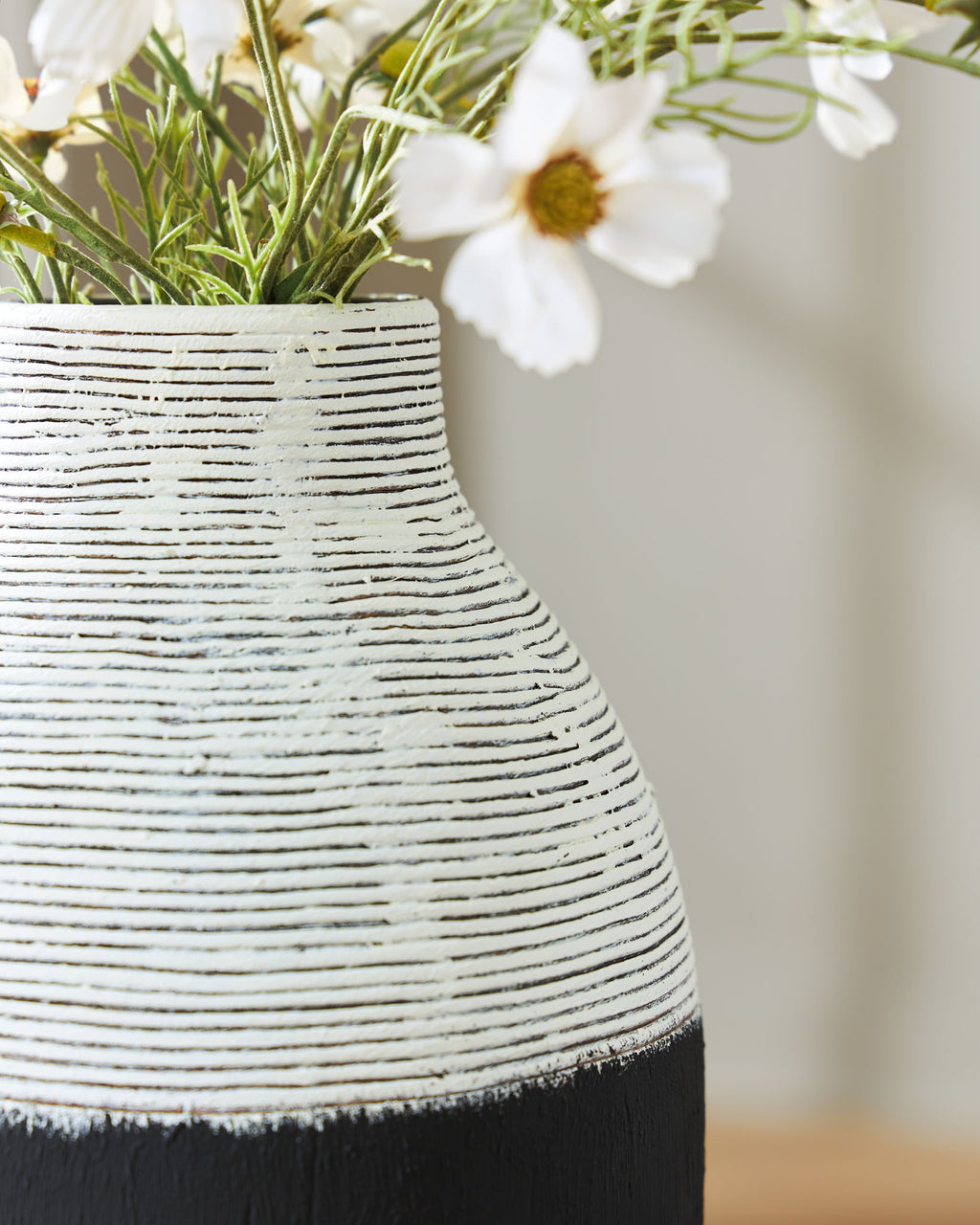 Close-up of black and white ceramic vase with textured horizontal stripes