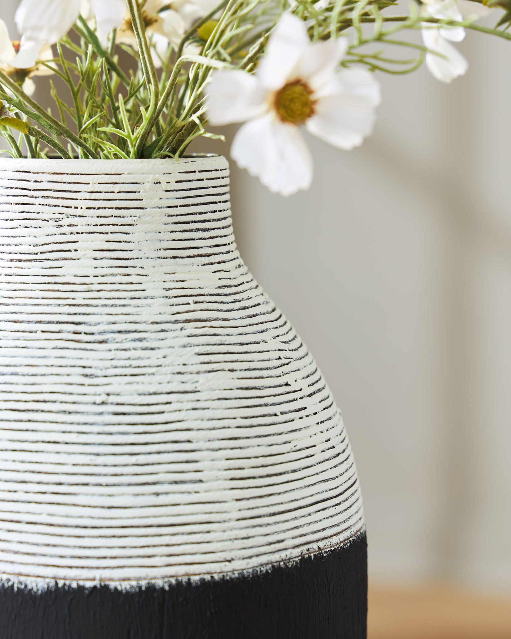 Close-up of black and white ceramic vase with textured horizontal stripes