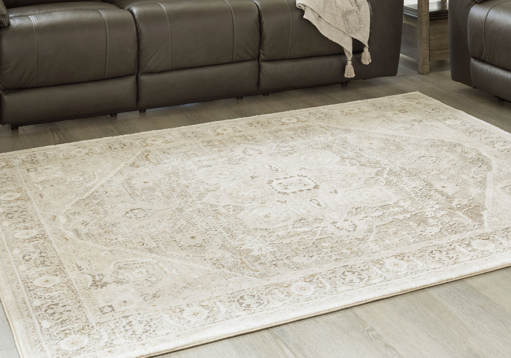 Beige area rug with faded ornate pattern, laid flat