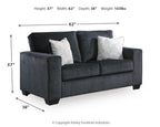 Dark gray stationary loveseat with two white patterned throw pillows and boxed seat cushions