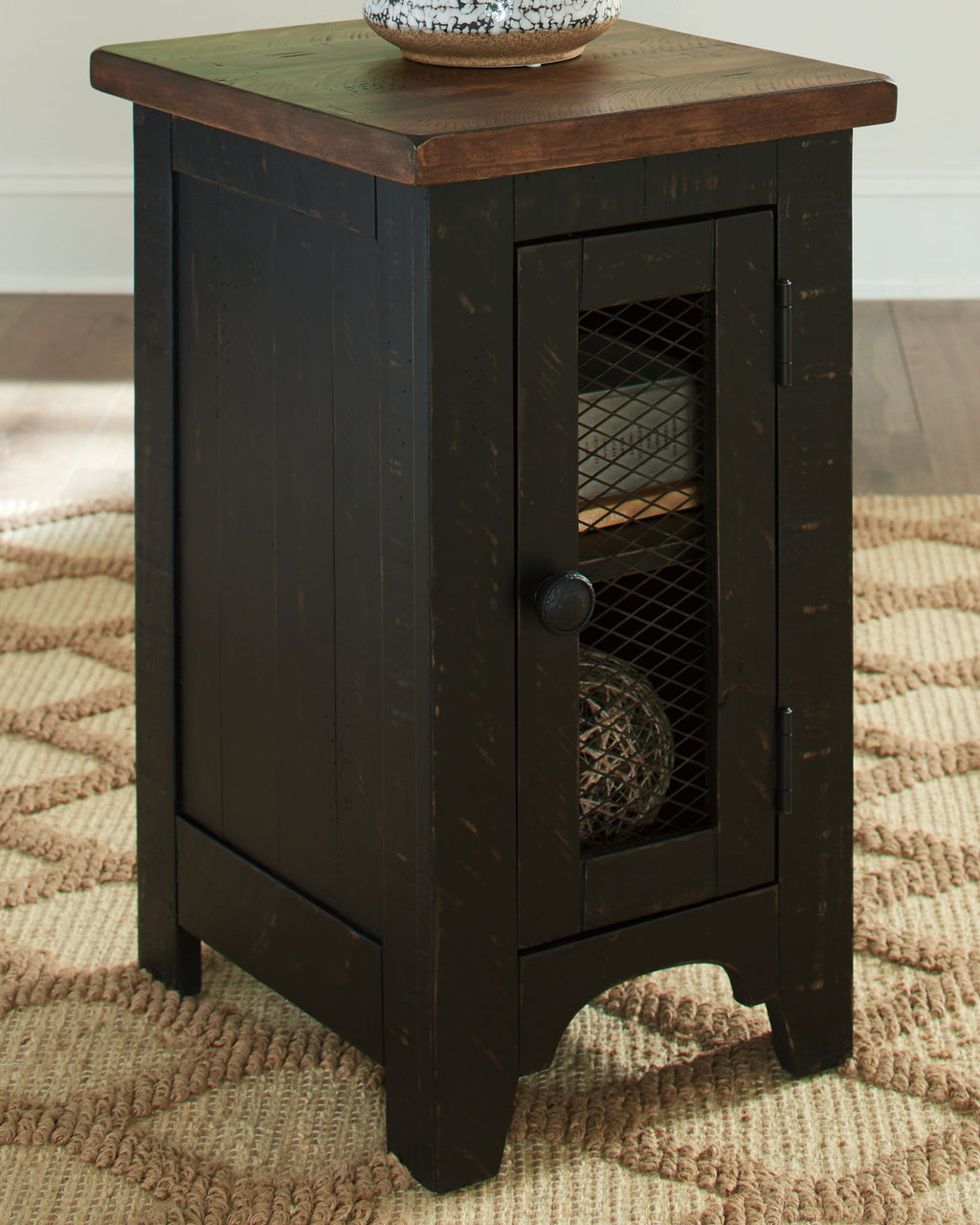 Black chair side end table with top surface and front door featuring wire mesh