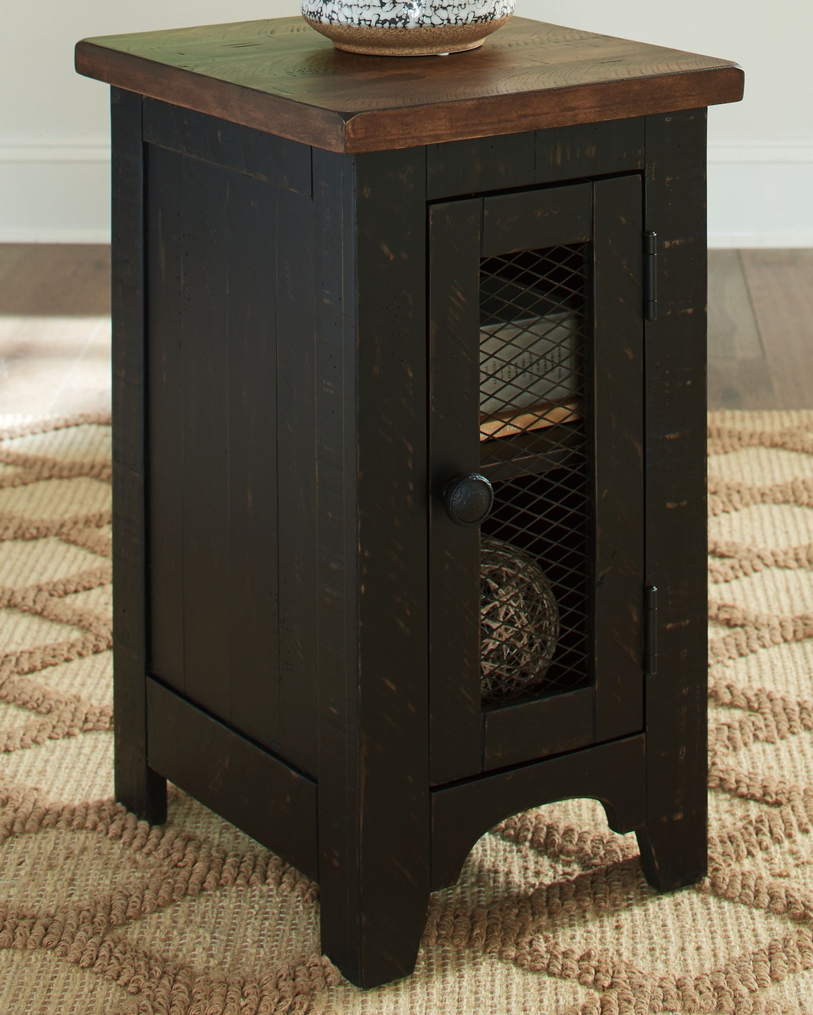 Black chair side end table with top surface and front door featuring wire mesh