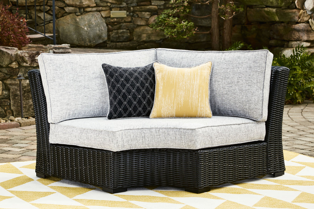 Black curved corner chair with light gray cushions and two decorative throw pillows