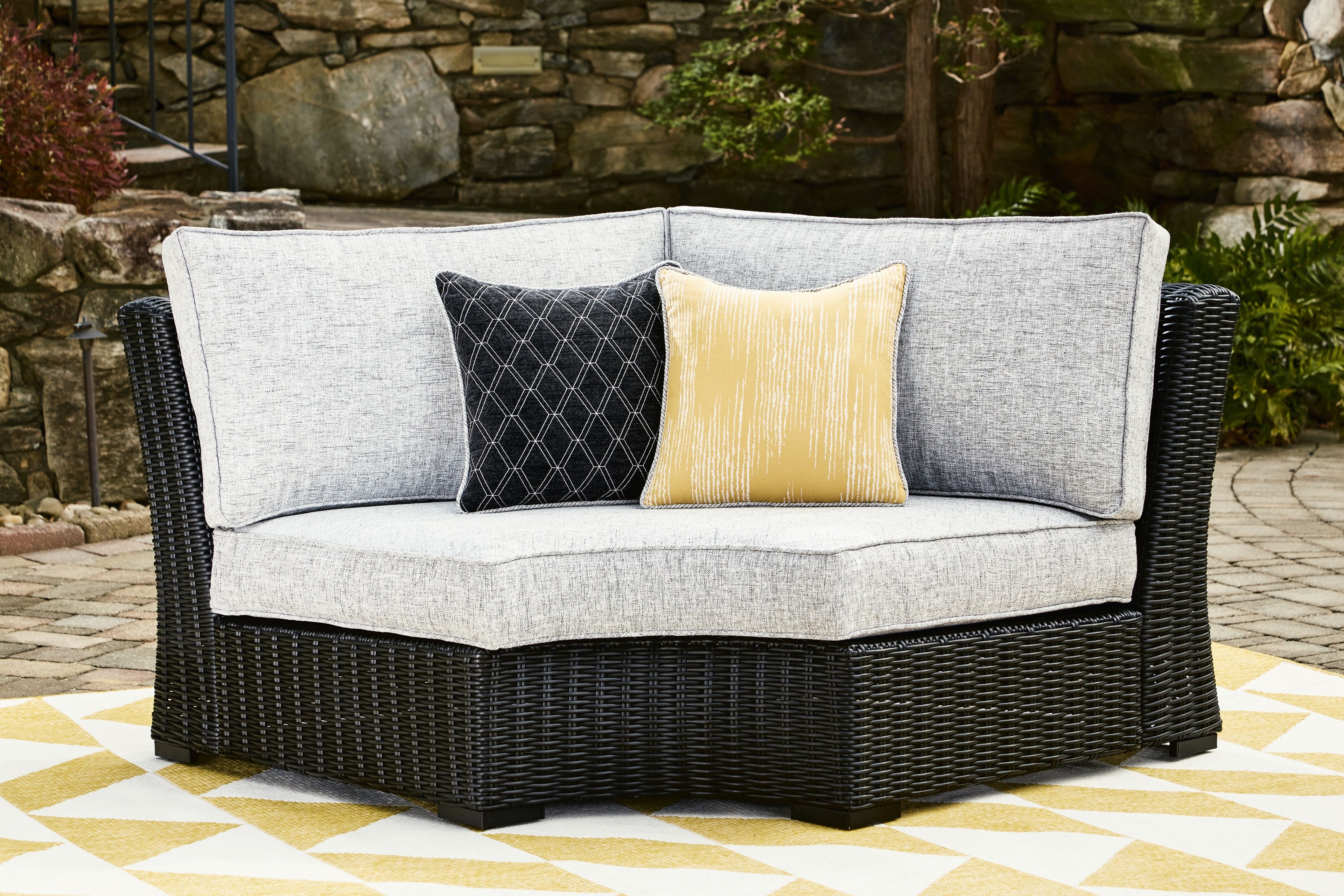 Black curved corner chair with light gray cushions and two decorative throw pillows