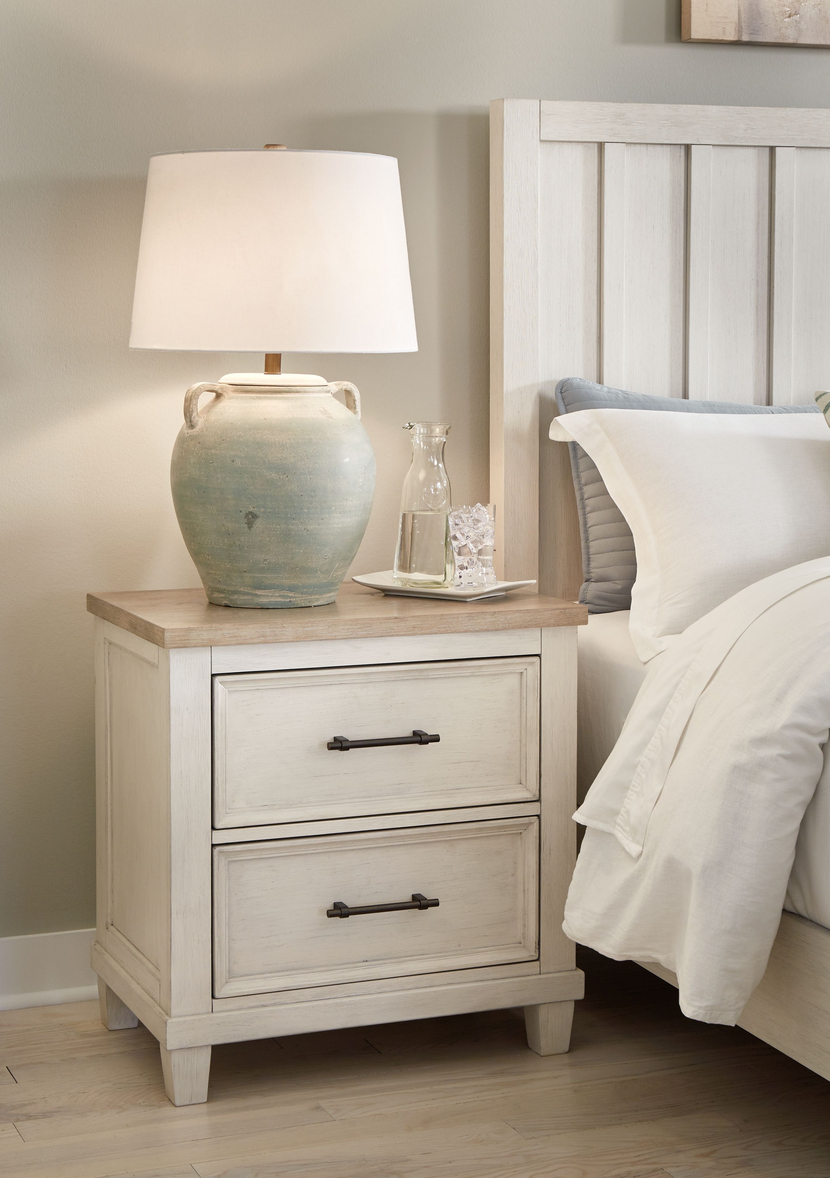 Antique white two-drawer night stand with slatted paneling and dark metal handles