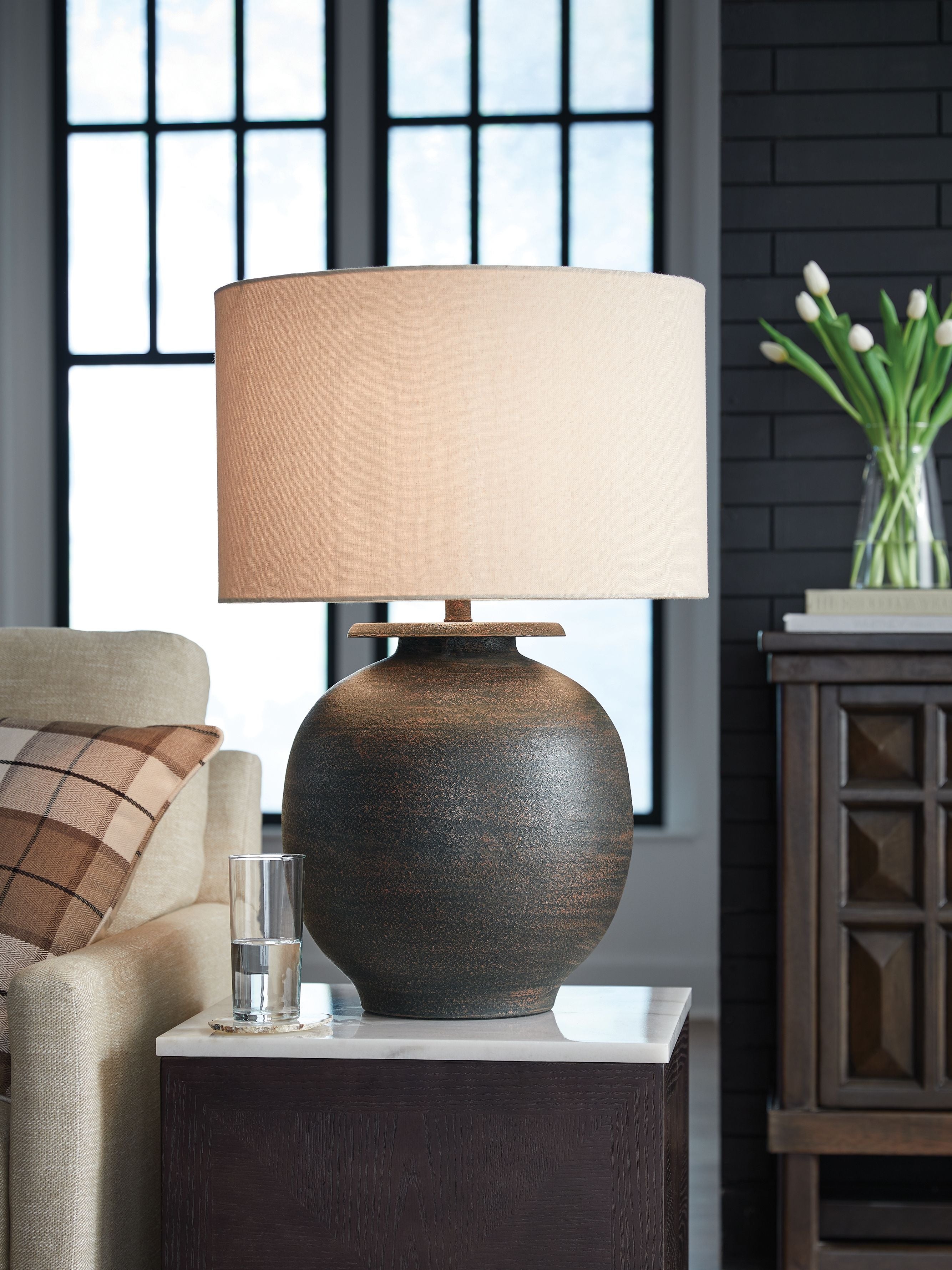 Antique brown metal table lamp on console with beige fabric drum shade