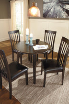Dark brown round dining table set with four slat-back chairs and black padded seats