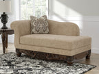 Beige corner chaise with patterned pillow and dark carved wooden base, front view.