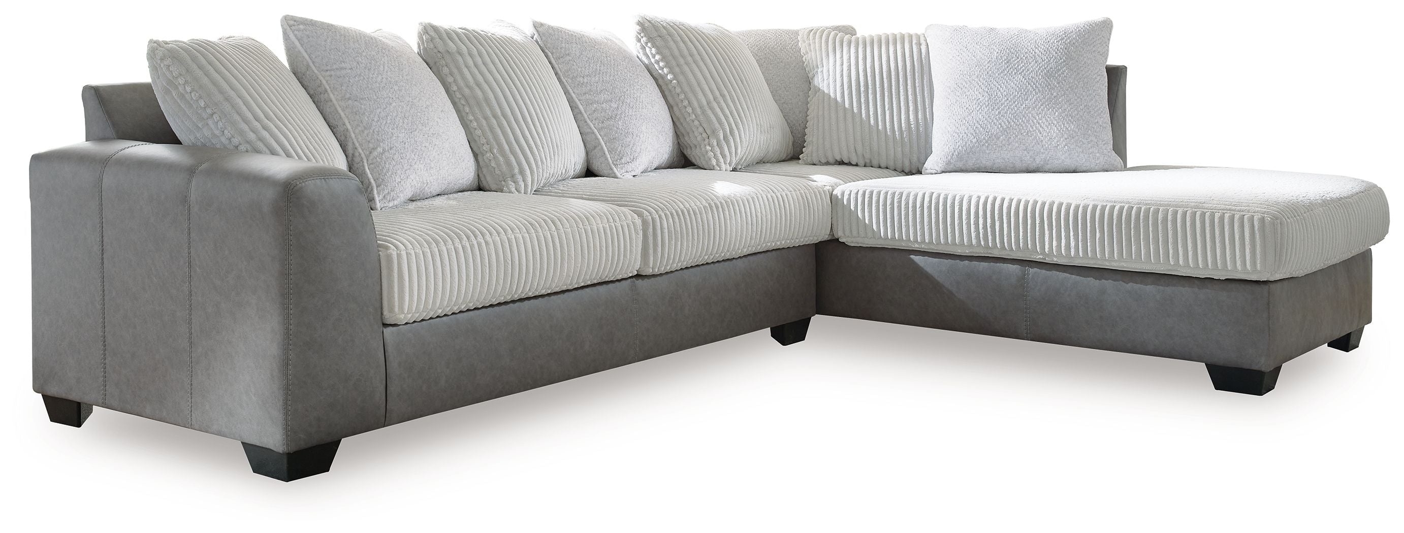 Light gray sectional sofa with corner chaise and multiple ribbed throw pillows.
