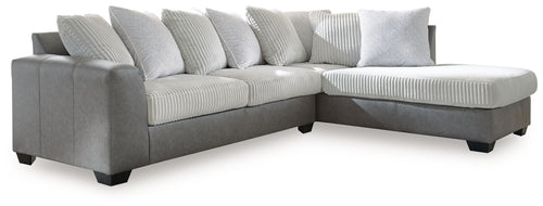 Light gray sectional sofa with corner chaise and multiple ribbed throw pillows.