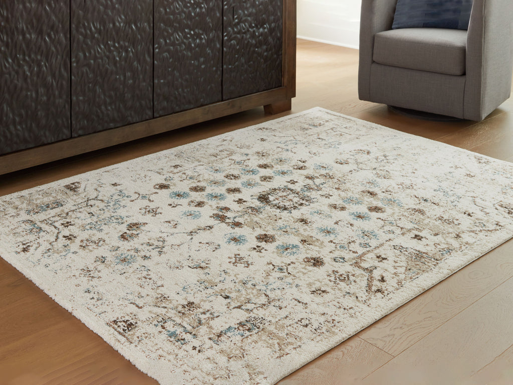 Beige area rug with distressed design in brown and blue-green on flat floor