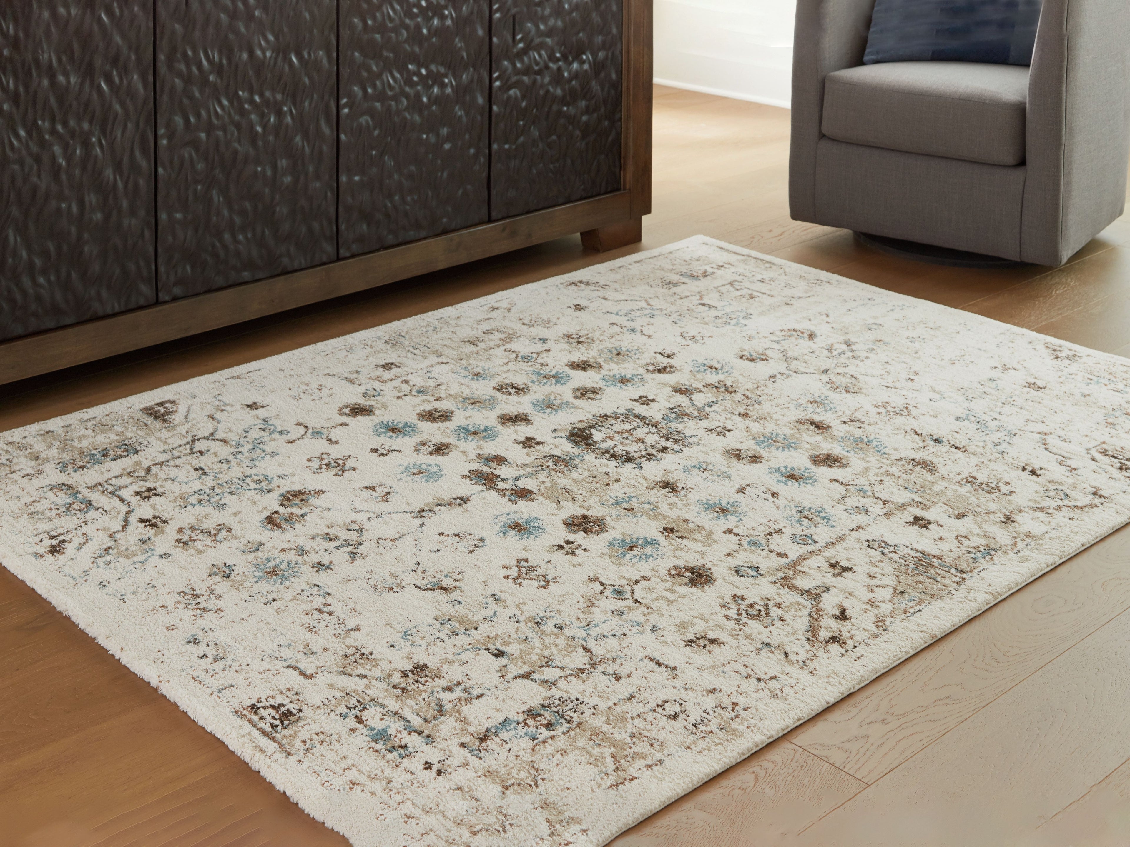 Beige area rug with distressed design in brown and blue-green on flat floor