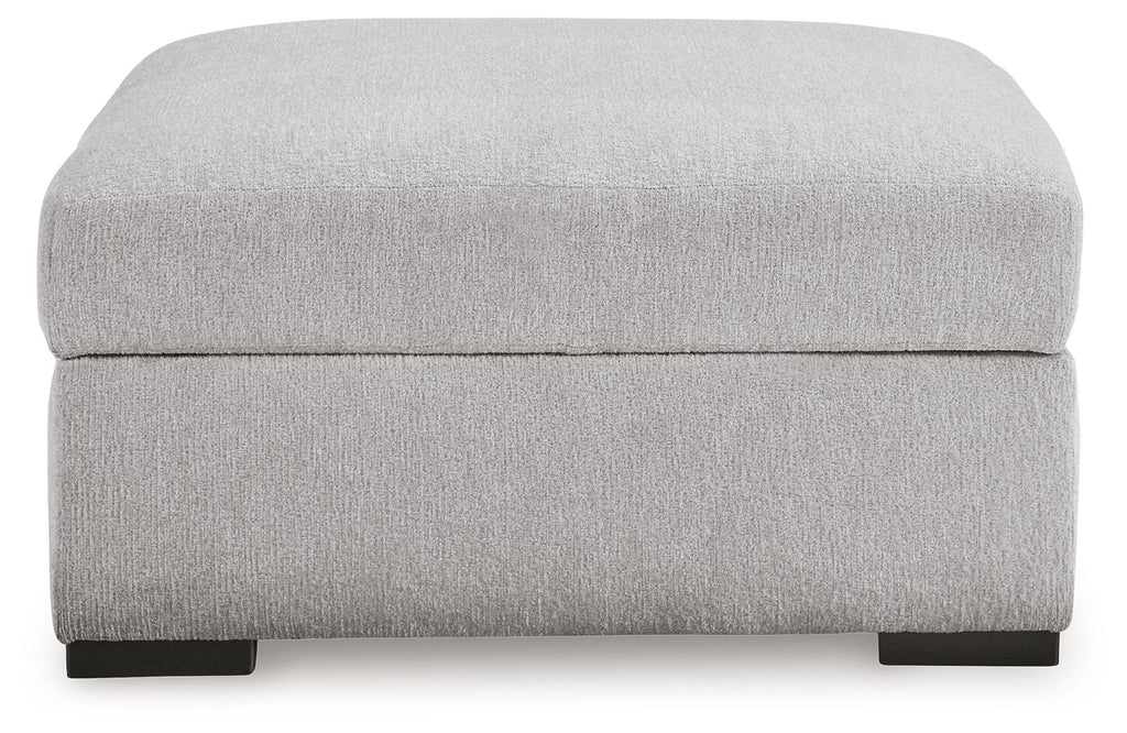 Light gray upholstered storage ottoman with hinged lid and dark feet