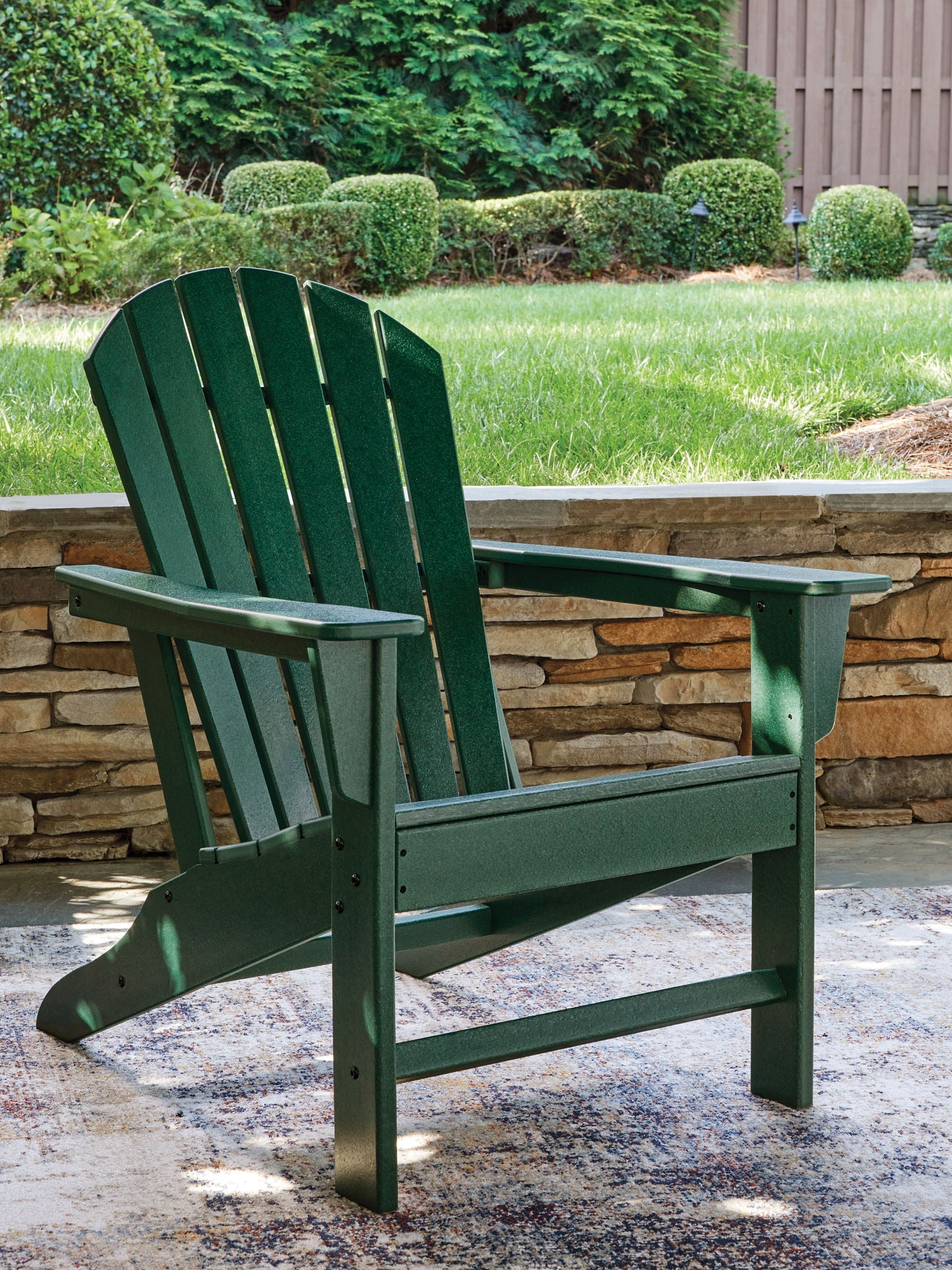 Green Adirondack chair with slatted back and seat, angled arms on sturdy legs.