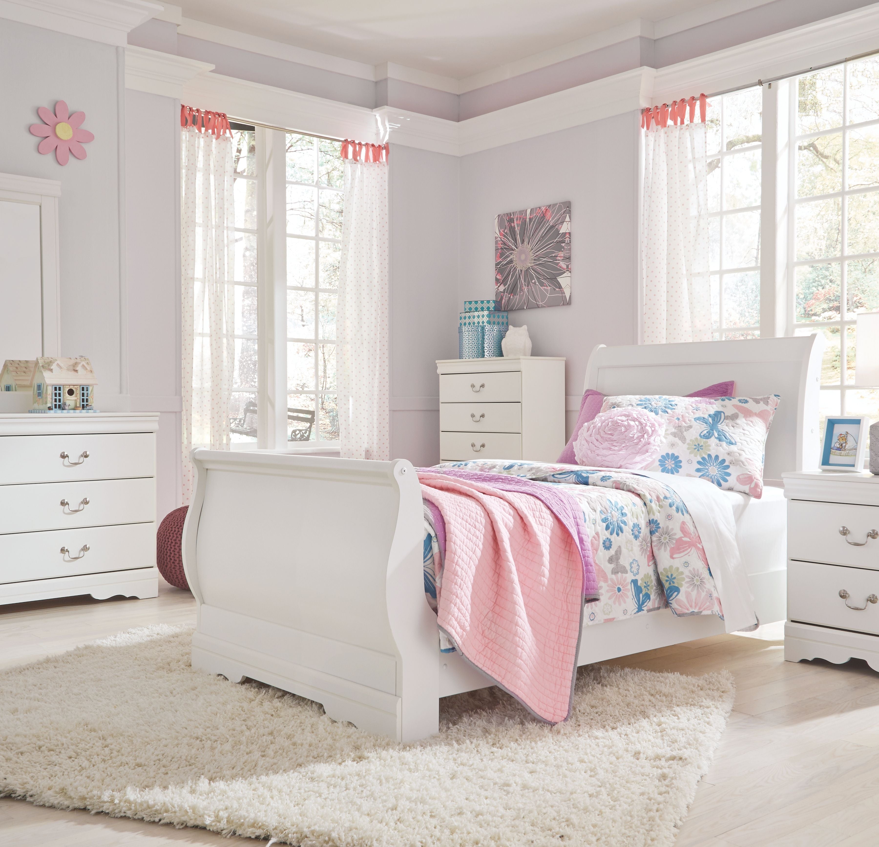 White sleigh bed headboard with rounded corners, floral duvet, and pillows