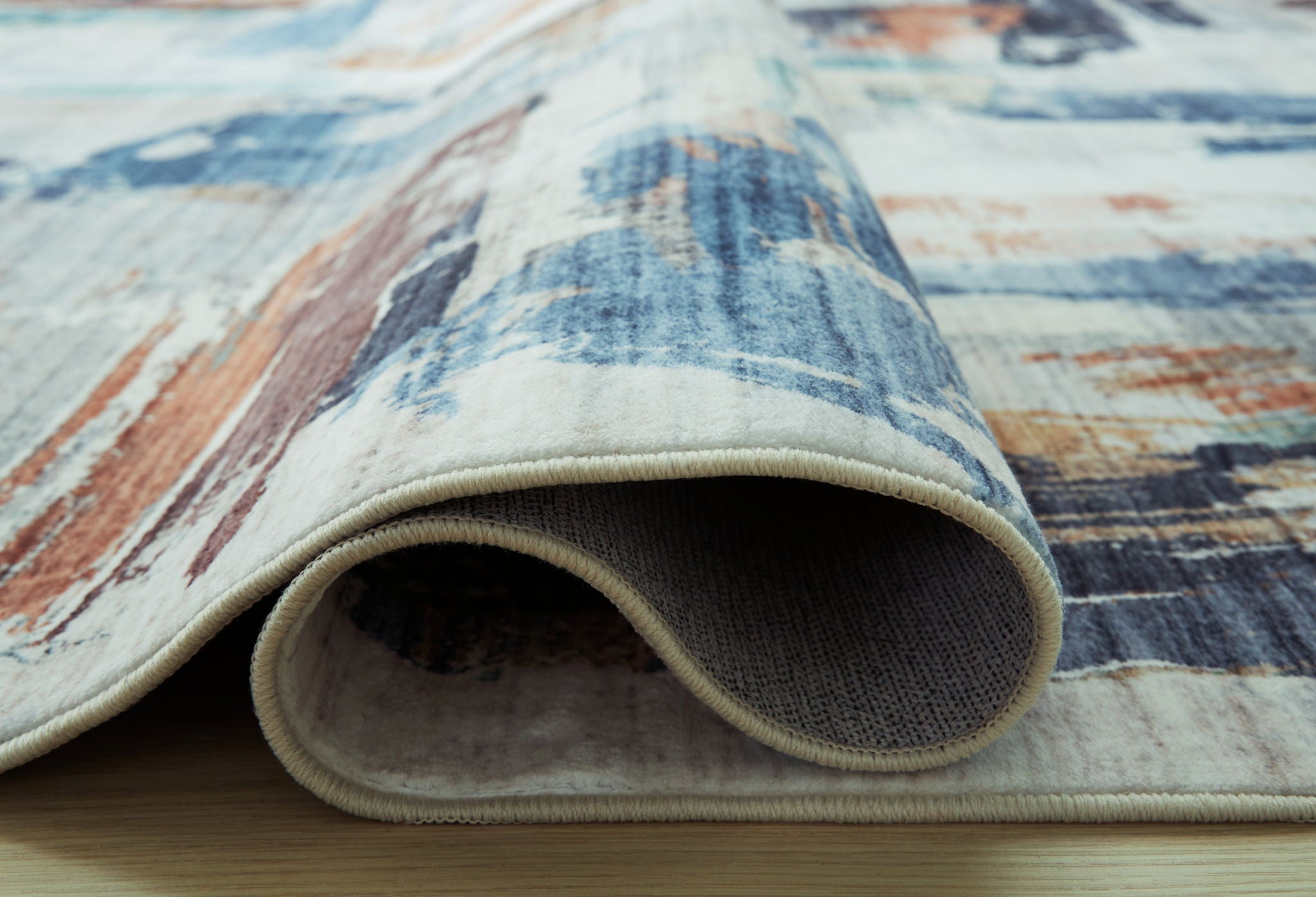 Washable rug corner with abstract blue-and-rust pattern and textured reversed backing