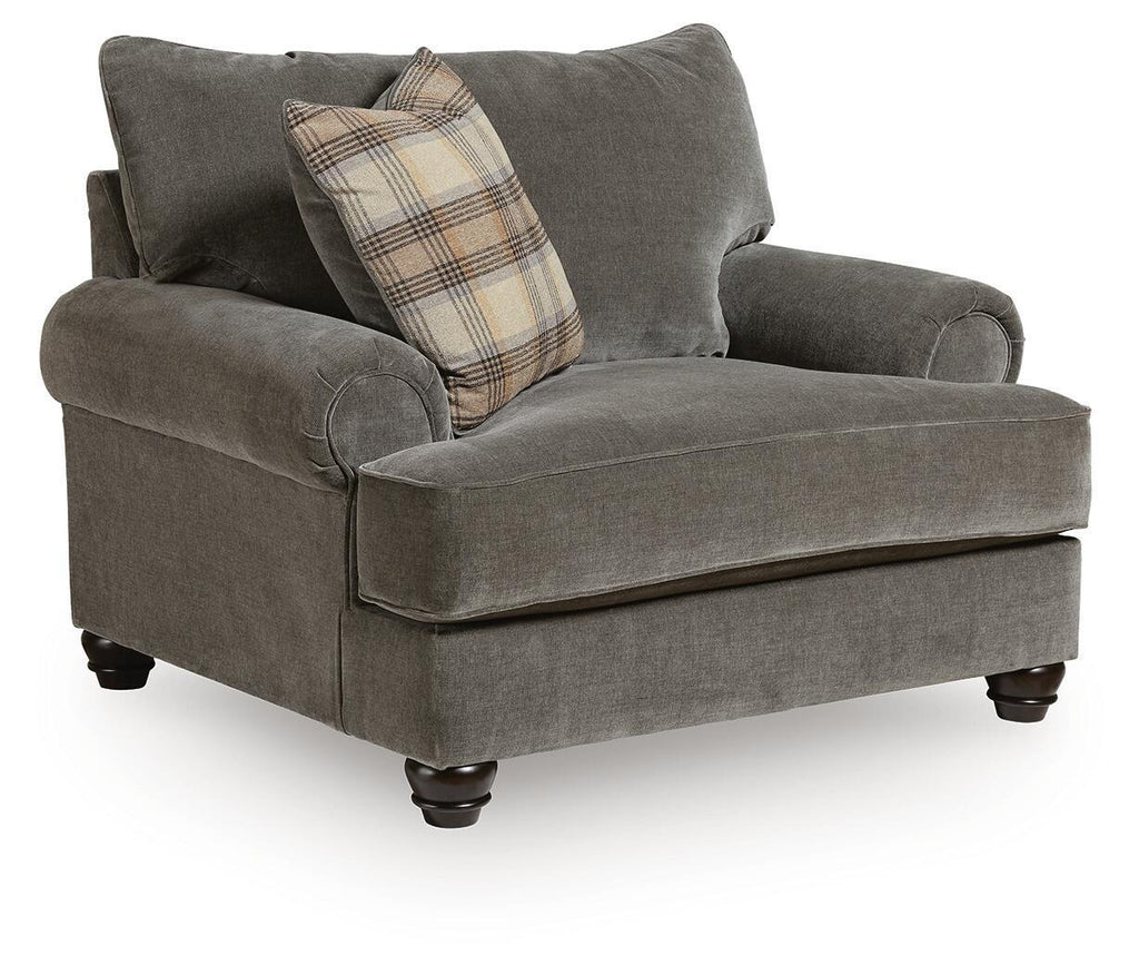 Gray chair-and-a-half with rounded arms, tufted back cushions, and plaid accent pillow