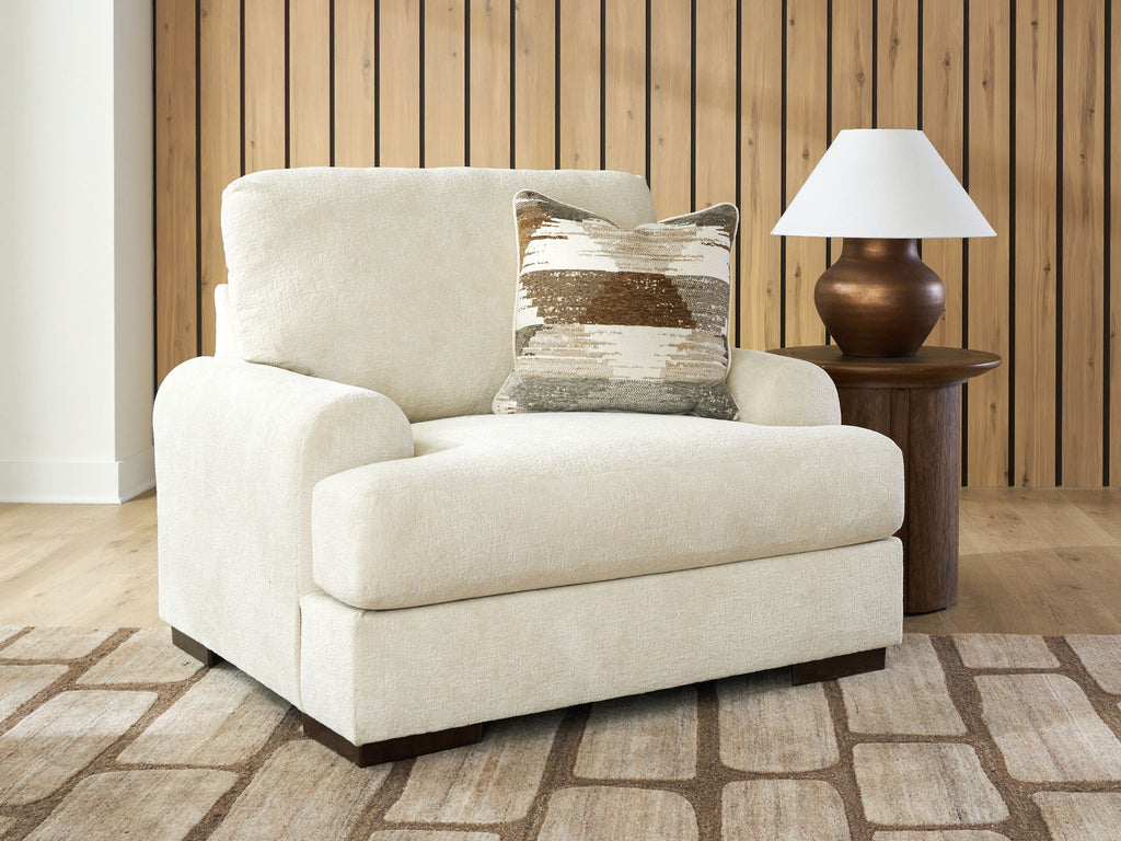 Beige armchair with wide arms, patterned throw pillow, and simple dark legs