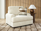 Beige armchair with wide arms, patterned throw pillow, and simple dark legs