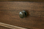 Brown wooden drawer front with round bronze-colored pull
