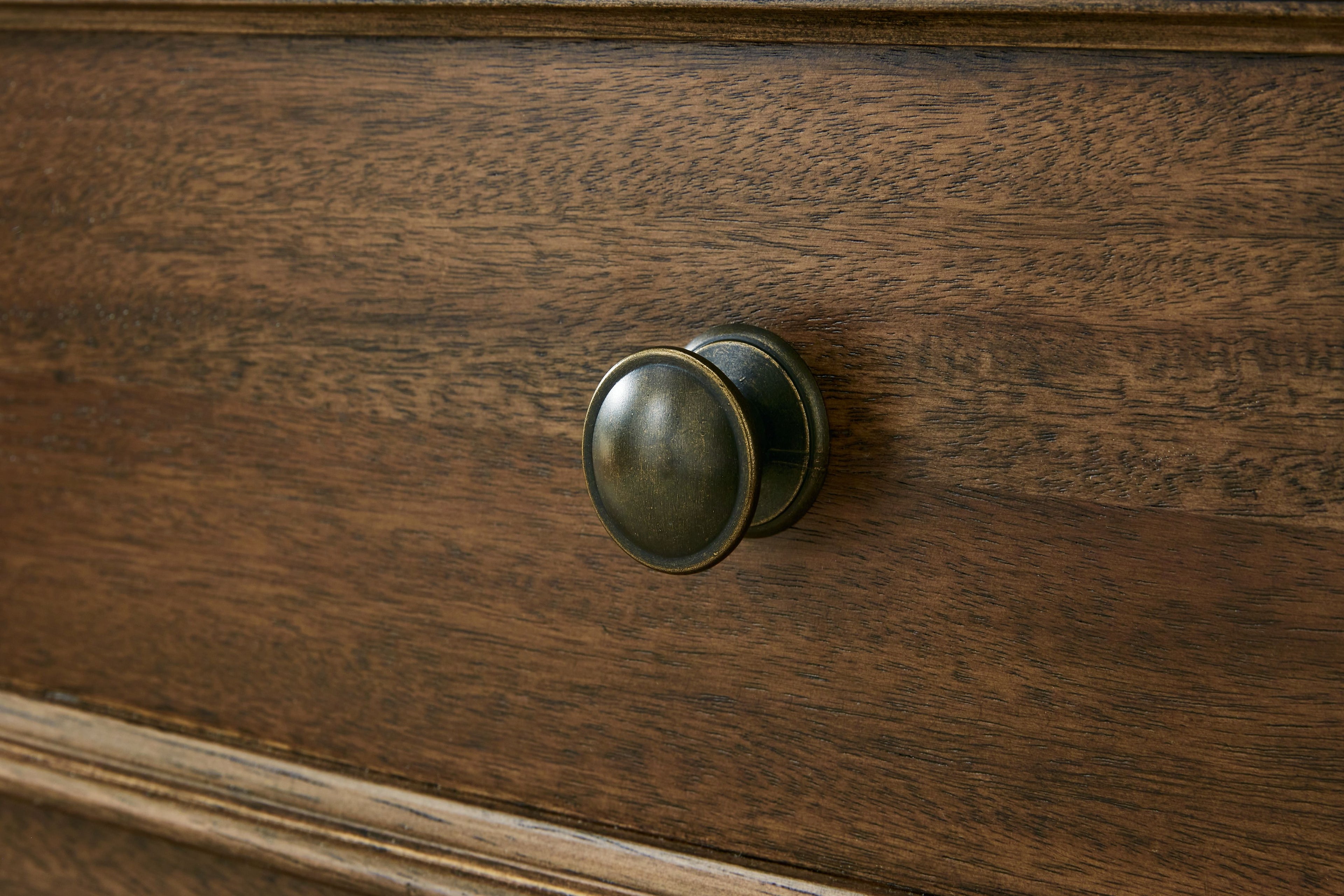 Brown wooden drawer front with round bronze-colored pull
