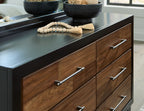 Brown wood dresser front detail with black top, three drawers and silver bar handles