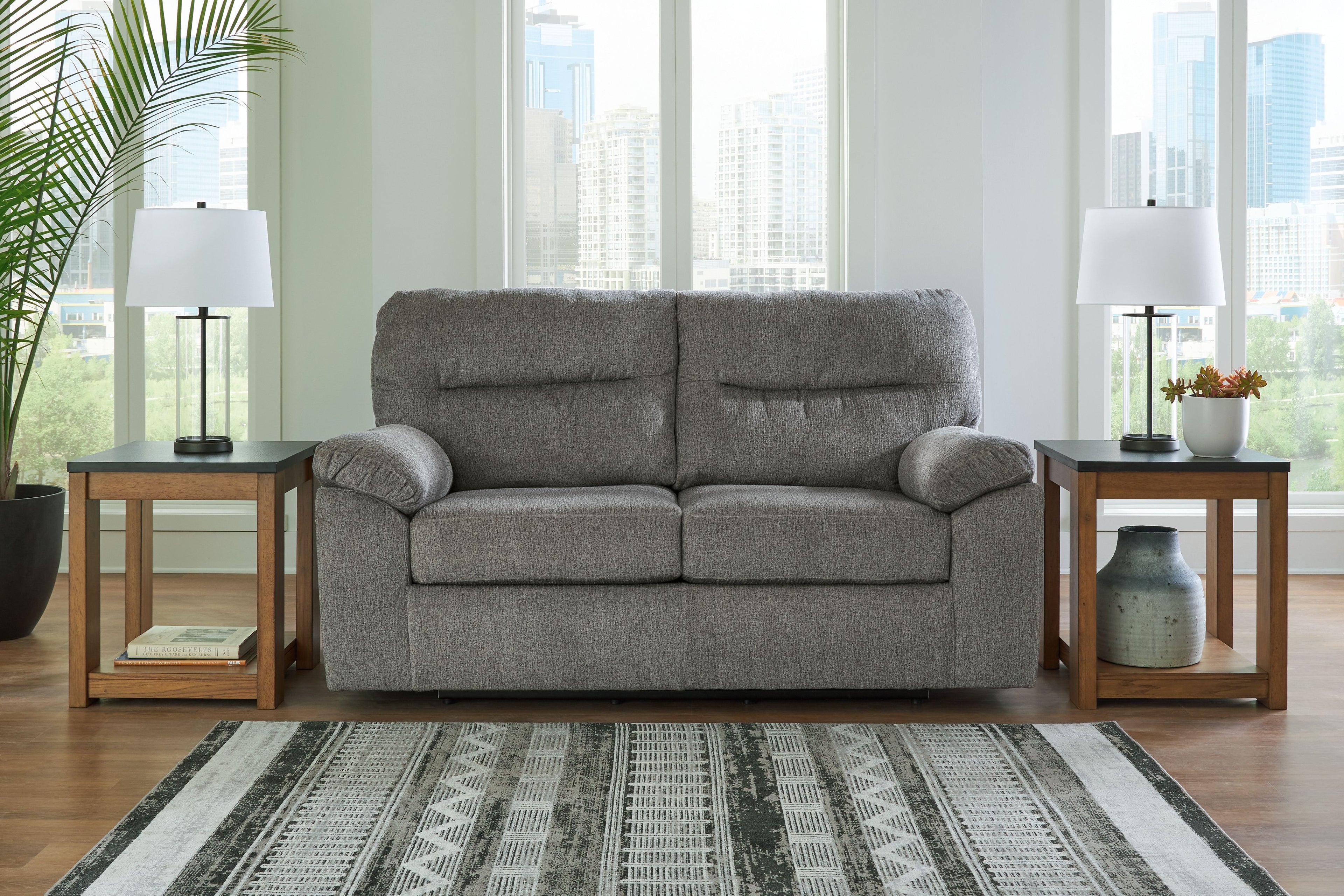 Dark gray glider loveseat with padded arms, two back cushions, and visible base legs
