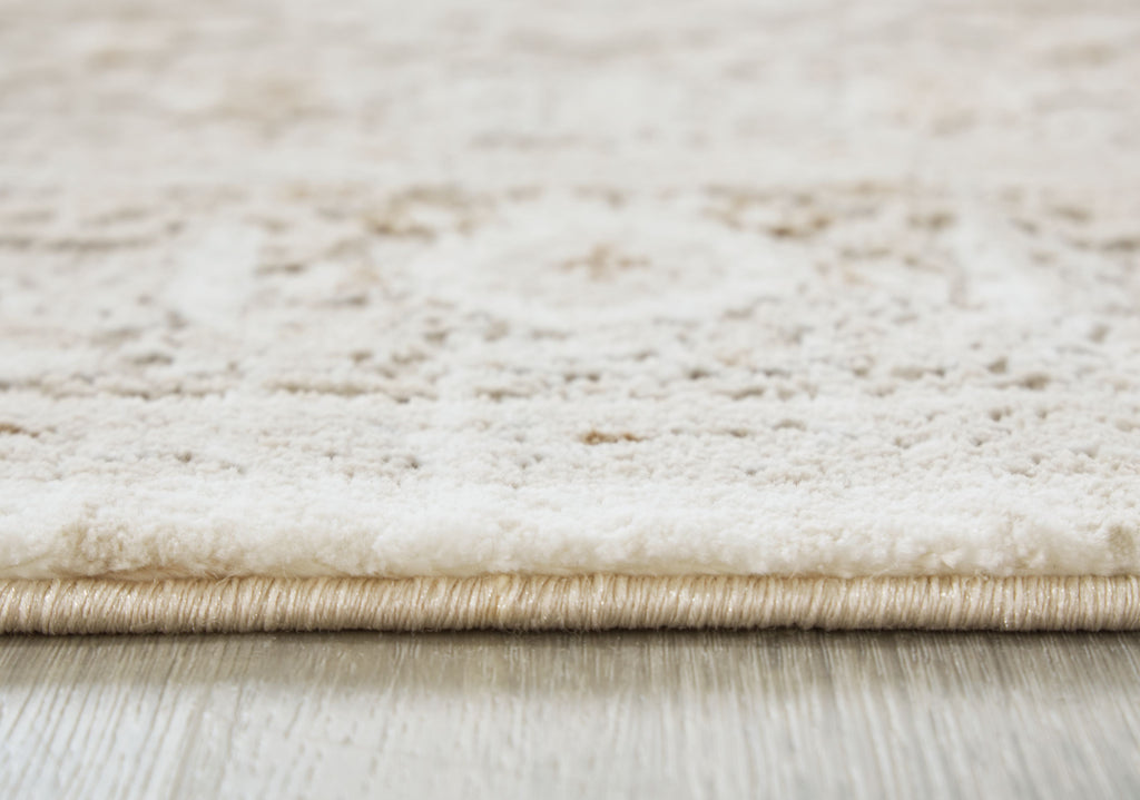 Beige rug pile close-up with bound edge and subtle distressed texture