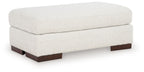 Cream upholstered ottoman with cushioned top and dark wooden feet, squared design