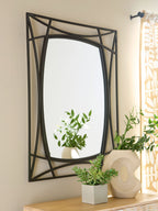 Black accent mirror with geometric frame on wall, with plants on nearby console