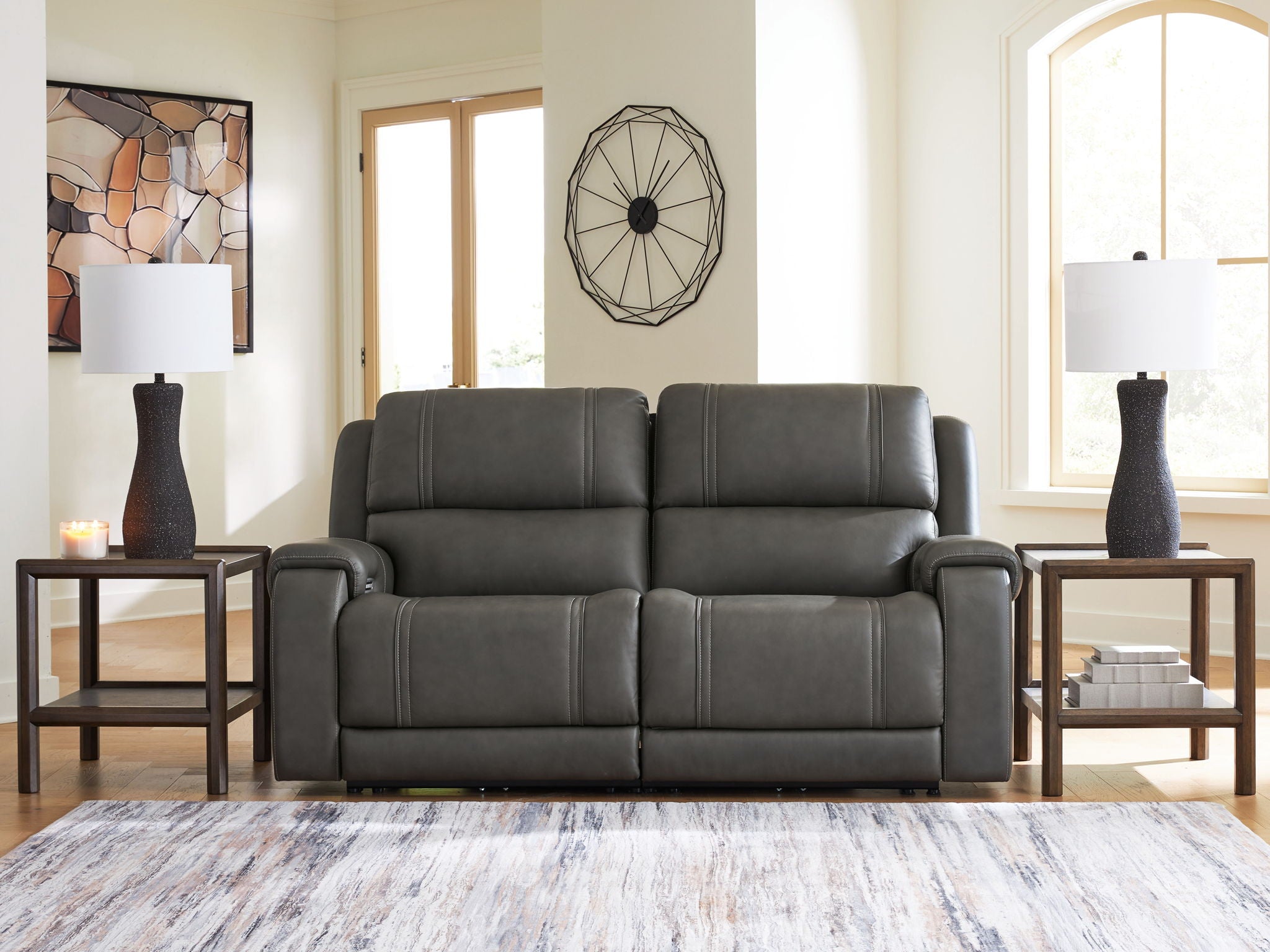 Dark gray reclining loveseat with wide padded arms and tufted seat back cushions