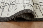 Beige rug with black border, folded edge showing textured pile