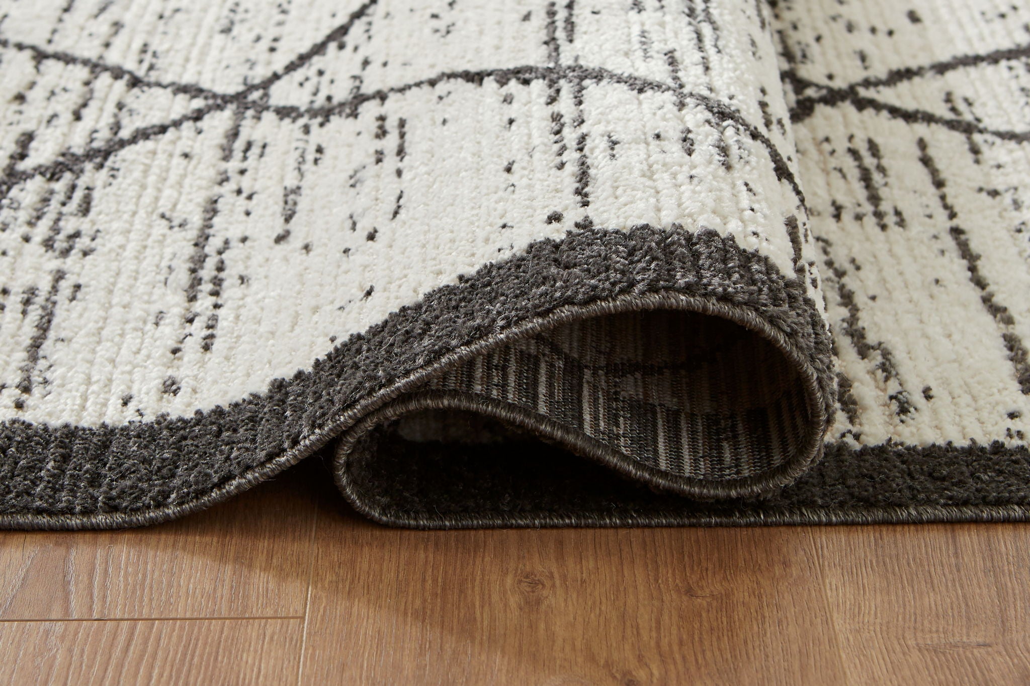 Beige rug with black border, folded edge showing textured pile