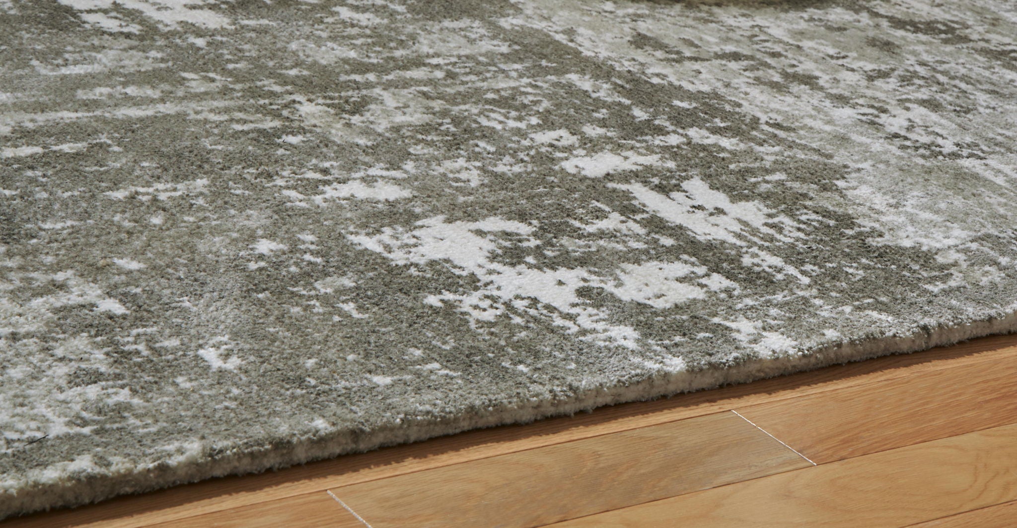 Dark gray area rug corner with distressed mottled pattern and low, dense pile