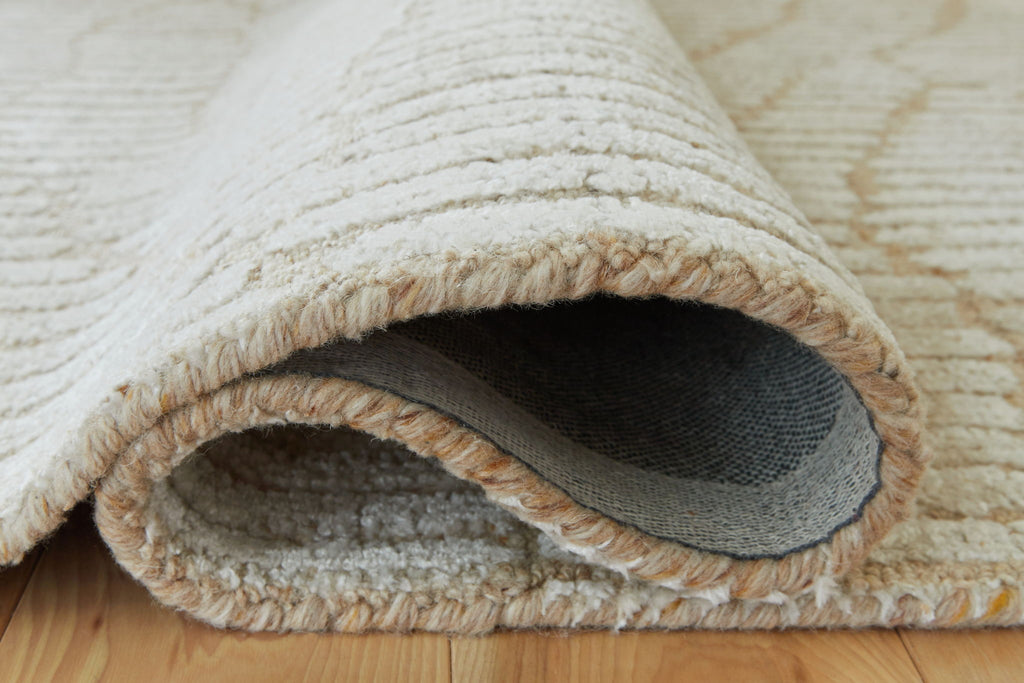 Beige rug edge with looped fringe trim and visible underside lining