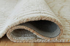 Beige rug edge with looped fringe trim and visible underside lining