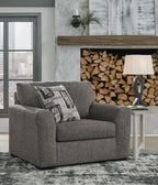 Gray chair and a half with patterned pillow, thick rolled arms, and square upholstered seat