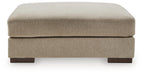 Oversized accent ottoman with padded rounded top in dune beige and short block legs.