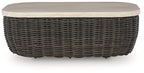 Dark brown wicker cocktail table with beige round-edged top and short profile