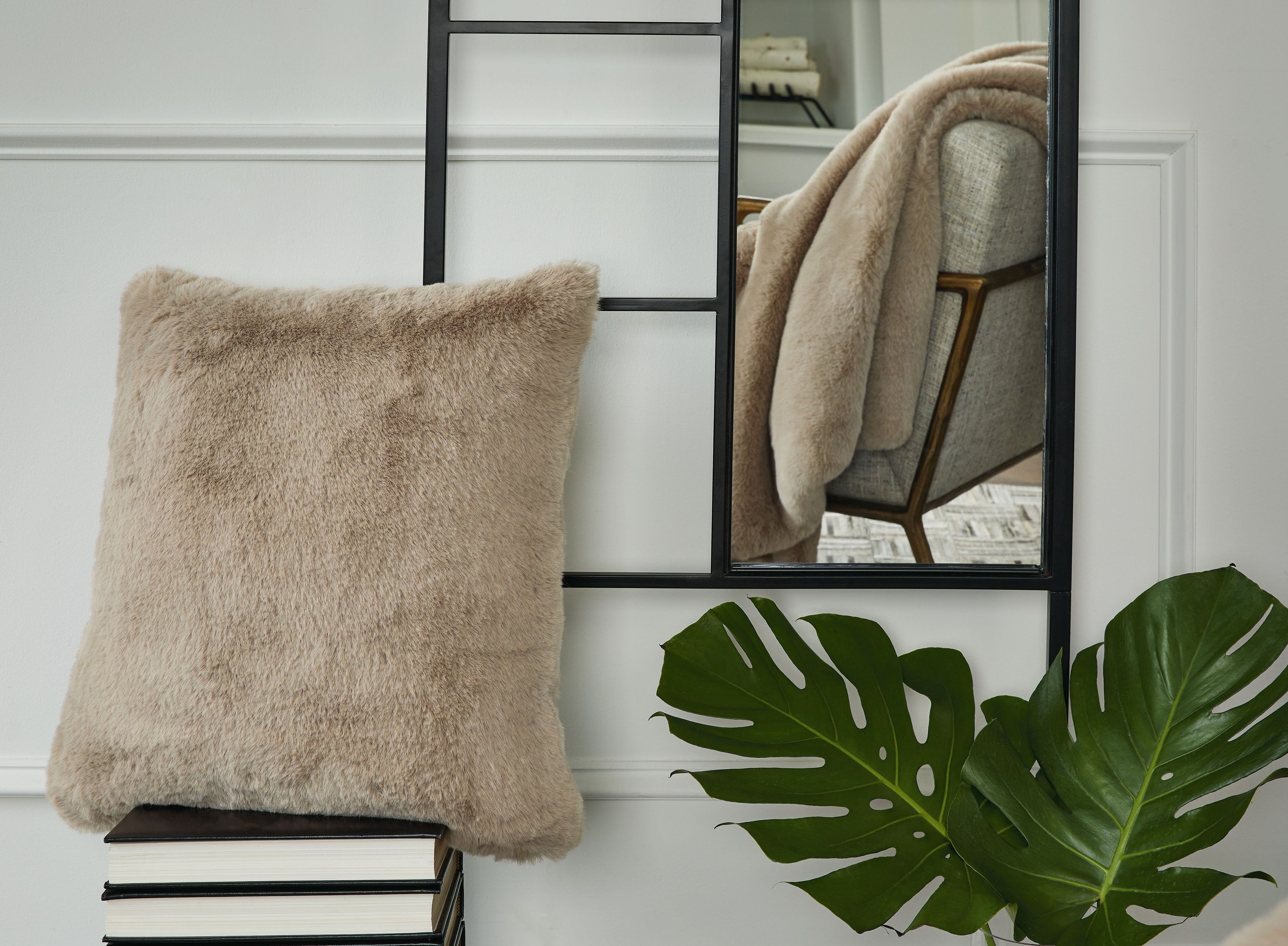 Beige faux fur square pillow with fluffy trim, placed upright on a shelf.