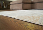 Beige distressed area rug with stitched edge and flat weave on hardwood