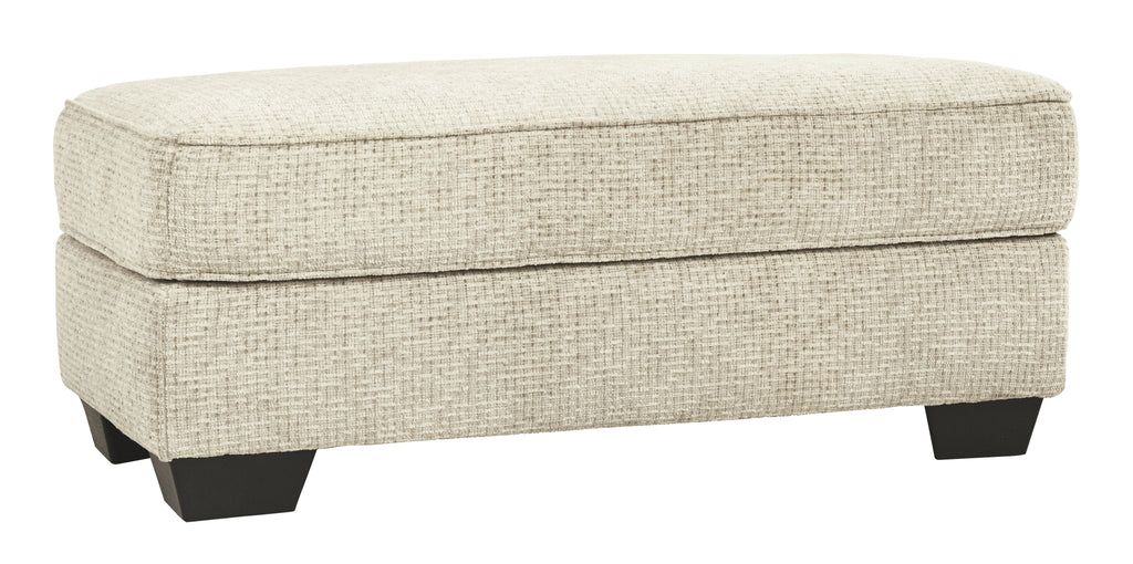 Sandstone upholstered ottoman with cushioned top and dark tapered legs