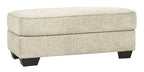Sandstone upholstered ottoman with cushioned top and dark tapered legs