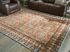 Brown area rug with repeating circular medallions and detailed border, flat woven texture.