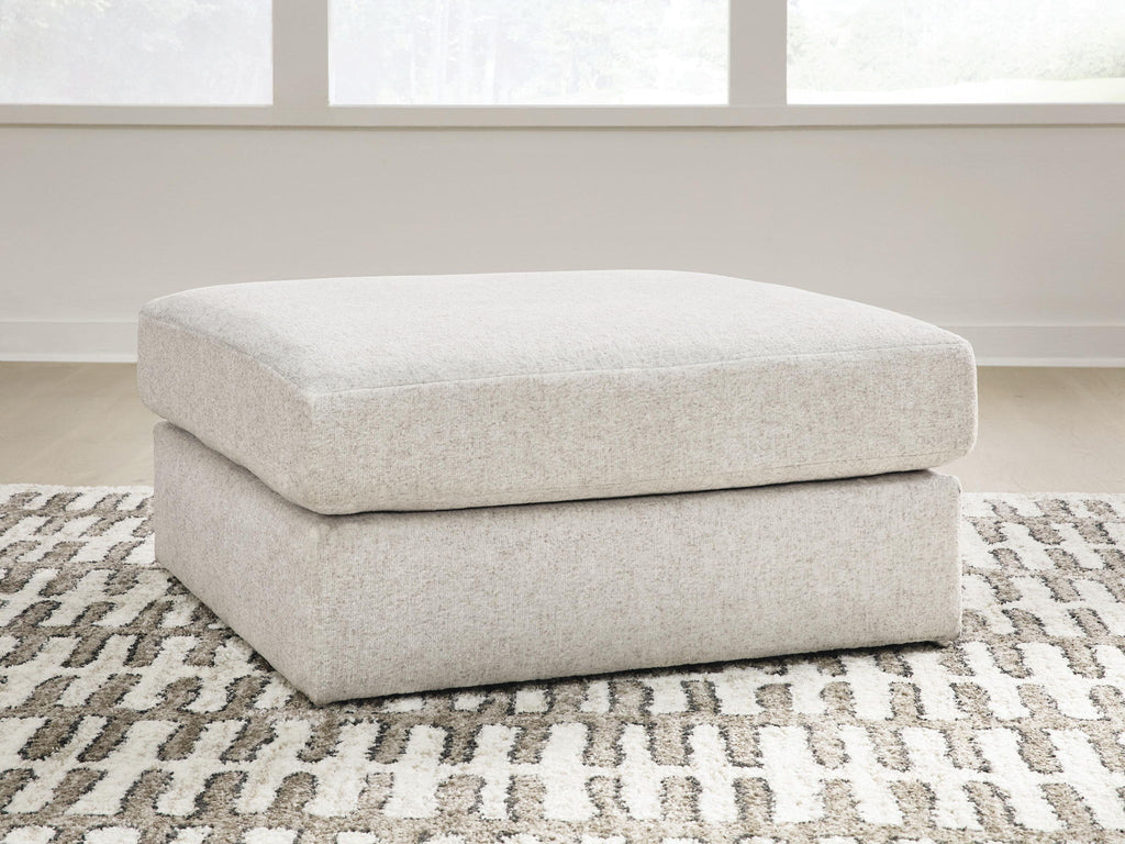 Light beige upholstered accent ottoman with rounded top and cushioned base