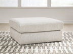 Light beige upholstered accent ottoman with rounded top and cushioned base